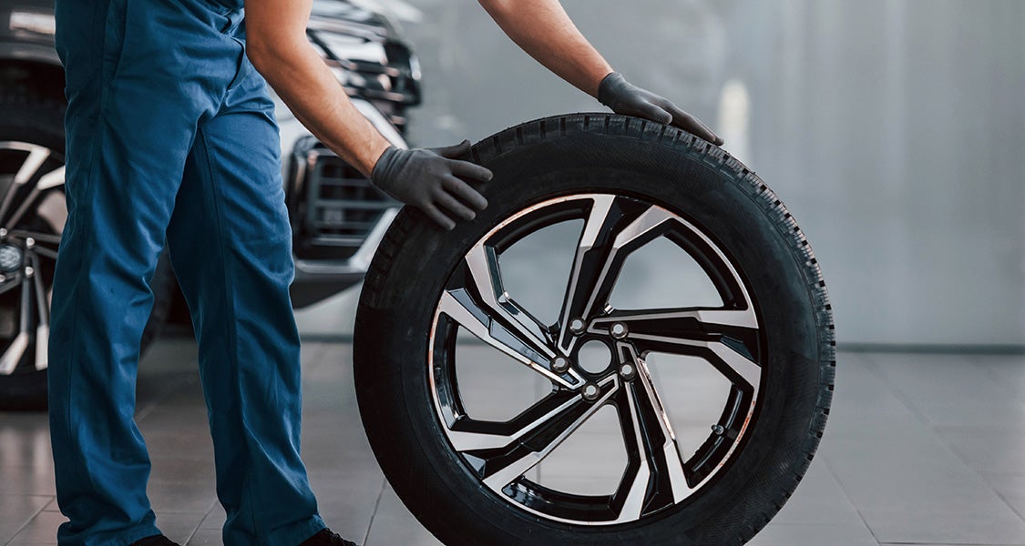 Technician lining up tires at auto service center